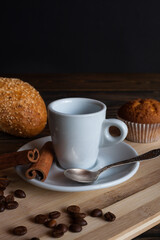 Coffee mug with coffee spoon, anise, cinnamon and cupcakes on an old table 