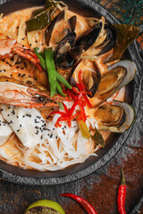 Delicious tom yam seafood Thai dish with freshwater prawn, mussels  plated on dark background