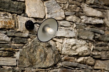 Old street light lamp on stone wall background. 