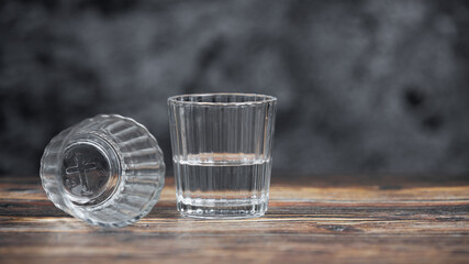 Bebida mexicana de agave mezcal tipo tequila hecha en oaxaca servida en veladora oaxaqueña sobre mesa de madera rústica acompañada de limón y sal de gusano 