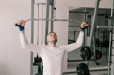 novice bodybuilder performs traction exercises on the simulator