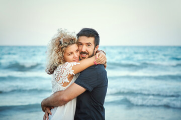 Young happy couple in love outdoors. loving man and woman walking on sea shore. - 427739906