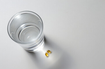 a glass beaker and two yellow tablets with vitamins. close-up.