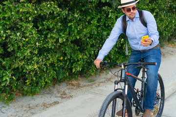 Obraz premium A businessman in casual clothes checks his cell phone while riding his bicycle.