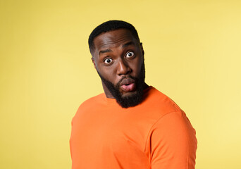 Obraz premium Black man with surprised and amazed expression. yellow background