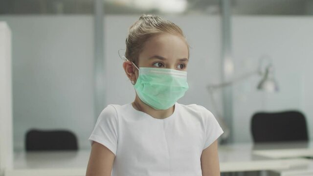 In the doctors office a child girl with a medical mask coughs