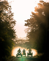 Silhouette of friends driving quad bike at sunset