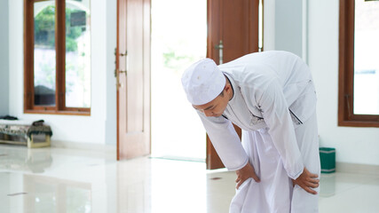 A portrait of an asian muslim man pray at mosque, the pray name is sholat, rukuk movement