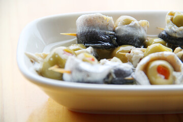 Anchovies with olives on the wooden table, appetizer