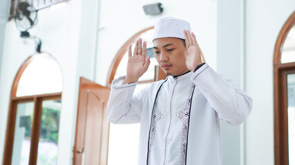 Naklejka na ściany i meble A portrait of an asian muslim man pray at mosque, the pray name is sholat, takbiratul ihram