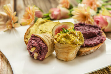 Close-up of a delicious breaktfast with bread and parfait, humus and fruits in a lovely arrangement with flowers on a wooden background