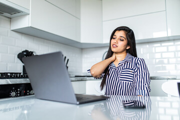 Obraz na płótnie Canvas Upset indian woman working from home office. Unhappy freelancer using laptop and the Internet. Workplace in cozy kitchen.