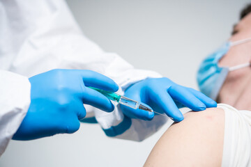 A doctor dressed in a protective suit vaccinates a patient against coronavirus.