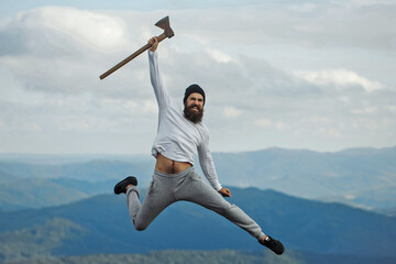 Carefree happiness freedom concept. Hipster man with beard and moustache in hat jumps with axe on...