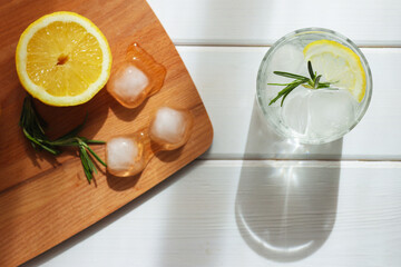 A glass of water with ice, lemon and rosemary. Refreshing summer drinks concept. Top view