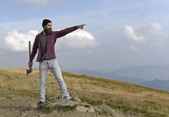 Man with ax on mountain. Carefree happiness freedom concept. Hipster man with beard and moustache in hat jumps with axe on mountain top on cloudy sky.