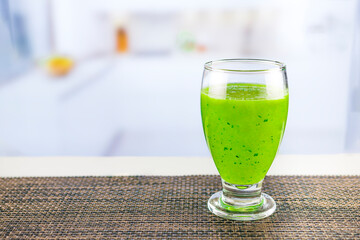Glass of juice with cucumber and parsley on white table, Detox cocktail of raw fruits and vegetables and lettuce and parsley, the background is out of focus