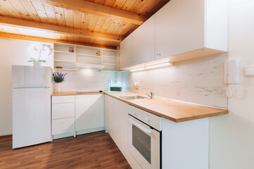 Kitchen at home with marble on wall, white cabinets, regular appliances and wooden work top, floor...