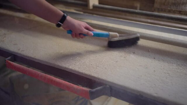 Cleans a workbench with a brush. Cleaning the workplace after work concept.