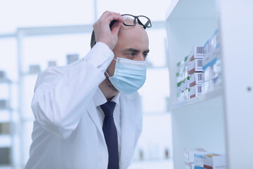 Man pharmacist in protective face mask working in drugstore