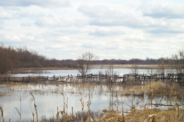 April cloudy landscape in flood of the river. Spring flood. Flooding meadows farms yard fence and gardens underwater