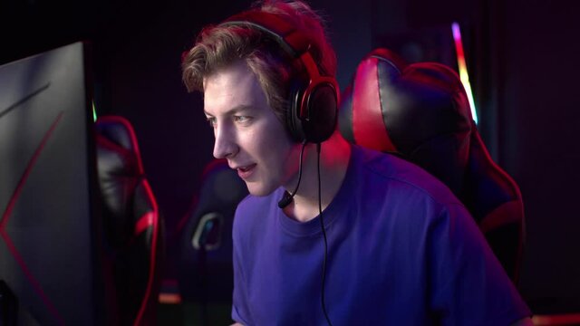 The novice gamer wins his first game in the tournament and raises his hands in joy and takes off his headphones