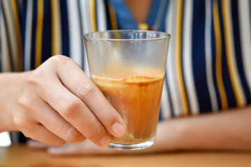 Dirty coffee in tall glass, Espresso shot mixed cold fresh milk in woman hand.