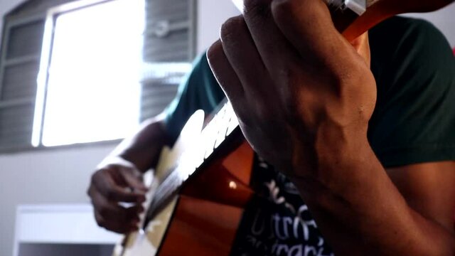 Homem negro tocando viol&atilde;o, &acirc;ngulo da c&acirc;mera contra plong&eacute;e.