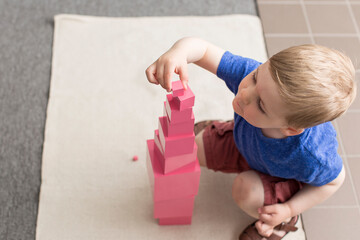 Little boy building Montessori pink tower