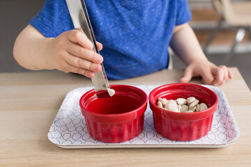 Little boy transferring beans into ceramic dishes while practicing practical life skills at a montessori preschool