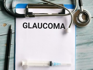 Medical and health concept. Phrase GLAUCOMA written on paper clipboard with stethoscope,syringe and a pen.