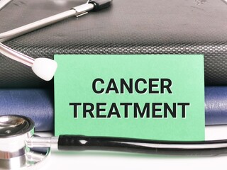 Medical and health concept. Phrase CANCER TREATMENT written on green paper card with stethoscope...