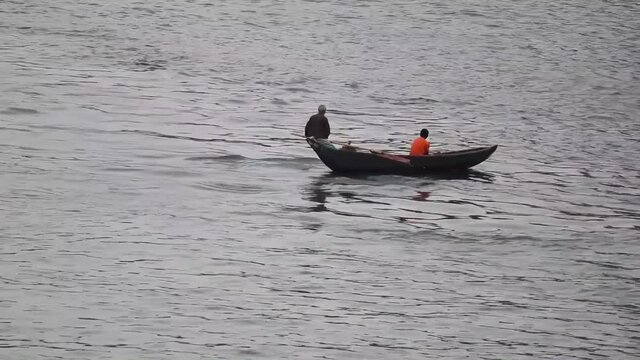 A small canoe takes a person across Buriganga River, Bangladesh, wide shot