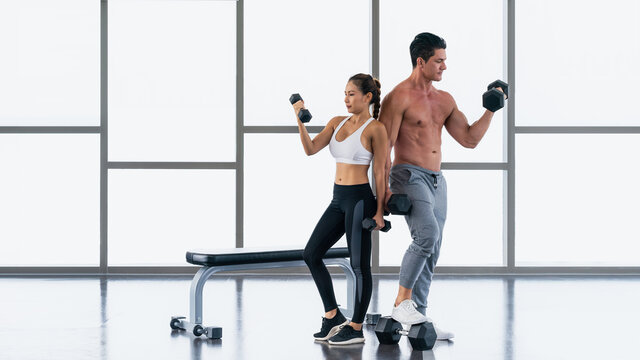 athletic couple workout with dumbbell weight lifting in gym and fitness - Powered by Adobe