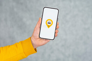 Phone display with Taxi icon on light background. Man holds a mockup smartphone in his hand...