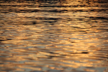 Golden yellow sunset reflection on the water surface of the lake