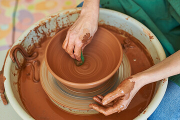 Close-up of female hands of a master potter working on a wheel with clay, view from above.
