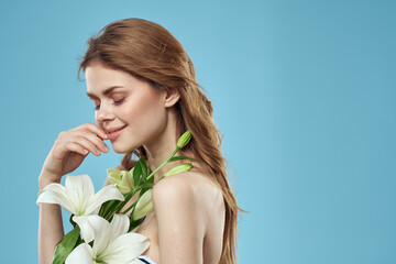 Woman with a bouquet of white flowers on a blue background naked shoulders beautiful face