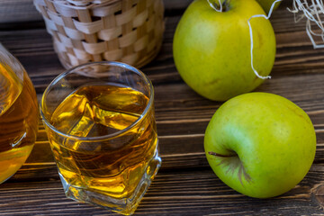 Green apples, basket with apples and jug with apple juice on wooden background