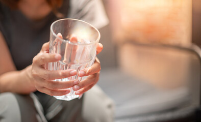 Female hand holding empty glass and sitting on the sofa in liveing room .for take a break with the depress emotion and stress feeling.