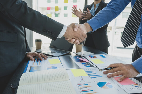 handshake after businesswomen and businessmen team meeting to plan strategies to increase business income. Have a brainstorming finance graph analysis and discussing for the new target success