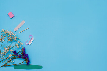 Manicure tools on a blue background are decorated with white gypsophila flowers. The concept of beauty. Copy space. top view