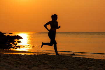Plakat Silhouette athletic woman jogging exercise and relax and freedom on sand beach. People running and workout in sunset background
