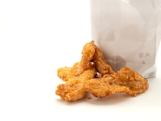 Fried bananas pouring outside of a paper bag placed on white background. Snack unhealthy concept