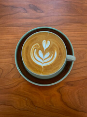 A cup of coffee with latte art on wooden table, top view