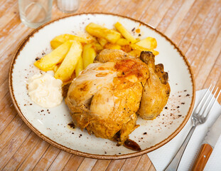 Homemade roasted chicken served on a ceramic plate with potatoes and sauce