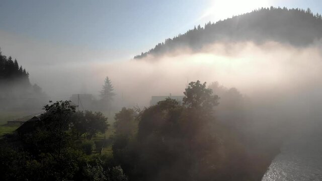 Summer sunrise in the foggy mountain village.