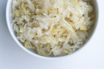 Top view of fresh homemade sauerkraut in a bowl isolated on a white background. Sauerkraut is finely cut raw cabbage that has been fermented by various lactic acid bacteria.