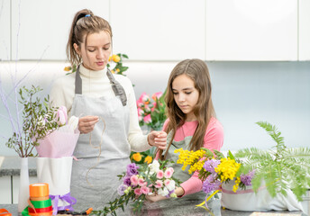 Woman teaches to young girl arranging flower