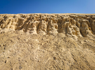 Formations of sand on the beach in Boa Vista Island, Cape Verde. Erosion of sandstone on the coast of Atlantic Ocean. Selective focus on the texture, blurred background.